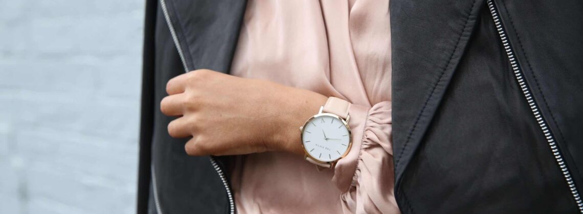 woman wearing peach dress, leather jacket, and watch on wrist